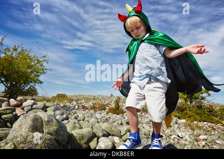 Boy wearing green cape walking on pebbles, Eggergrund, Sweden Stock Photo