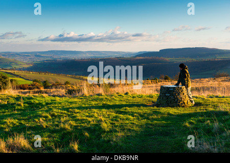 A rambler pauses to admire the view from the toposcope on Bury Ditches Iron Age hill fort in South Shropshire near Clun, England Stock Photo
