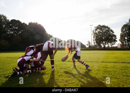 Teenage schoolboy rugby team taking ball from huddle Stock Photo