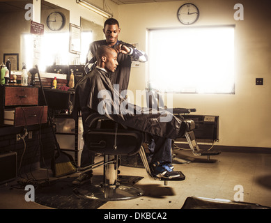 Barber in traditional barber shop shaving man's head Stock Photo