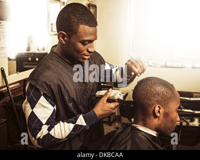 Barber in traditional barber shop shaving man's head Stock Photo