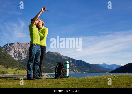 Young happy couple with backpack making photo of themselves near mountain lake Stock Photo