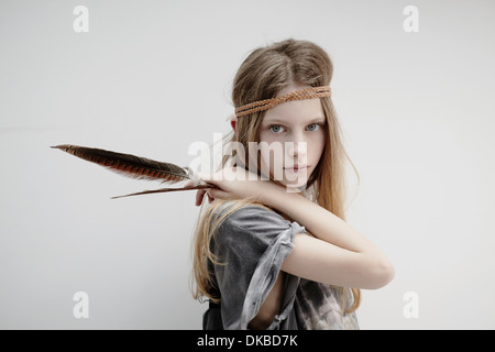 Portrait of girl wearing leather braid around head, holding feather Stock Photo