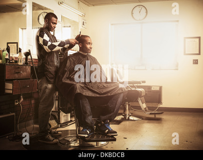 Barber in traditional barber shop shaving man's head Stock Photo