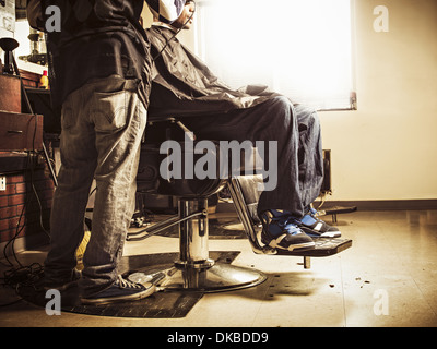 Barber in traditional barber shop shaving man's head Stock Photo