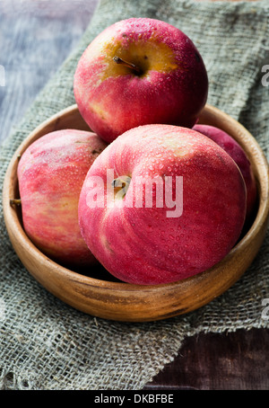Red apples in wooden bowl over rustic background, selective focus Stock Photo