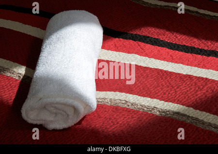 Rolled white towel on bed. Stock Photo