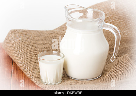 Composition milk in a jug, a glass on burlap background Stock Photo