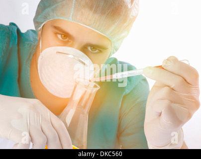 Scientist dropping liquid into flask Stock Photo