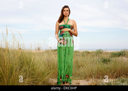 Pregnant woman standing in field Stock Photo