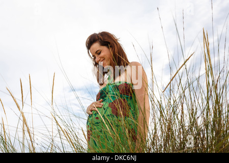 Pregnant woman standing in field Stock Photo