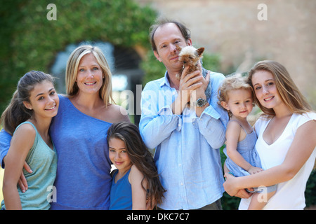 Parents standing with daughters and dog in garden Stock Photo