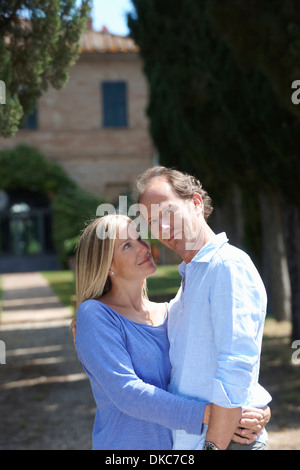 Mature couple standing in garden hugging Stock Photo