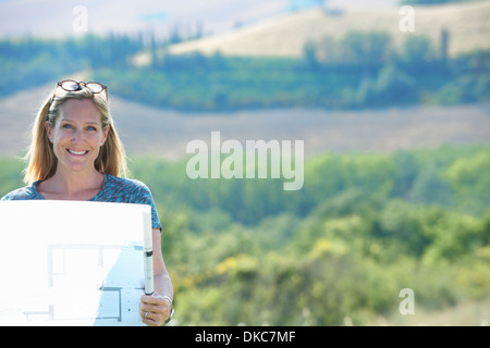 Mature woman standing on mountain looking at architects plans Stock Photo