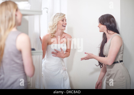 Young woman trying on wedding dress, with friends Stock Photo