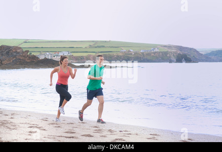 Couple running on beach, Thurlestone, Devon, UK Stock Photo