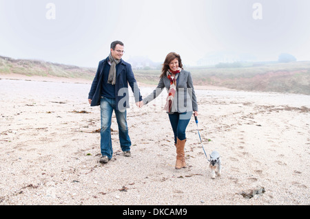 Couple walking with dog on beach, Thurlestone, Devon, UK Stock Photo