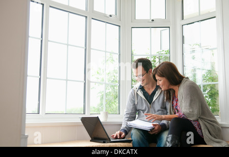 Couple on window seat, using laptop Stock Photo