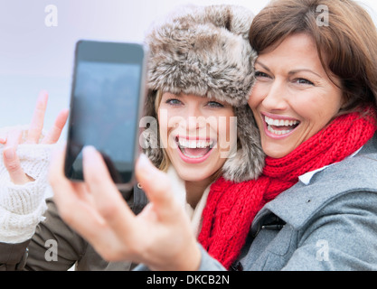 Two female friends taking self portrait at coast, Thurlestone, Devon, UK Stock Photo