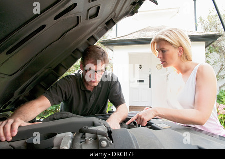 Adult couple checking under car hood Stock Photo