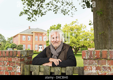 Senior man leaning on wooden gate Stock Photo