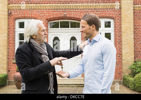 Father giving son key outside house Stock Photo