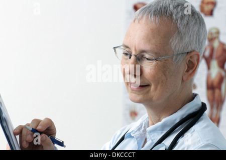 a laughing  woman doc with a human muscle person poster in the background and with a pen on laptop or desktop Stock Photo
