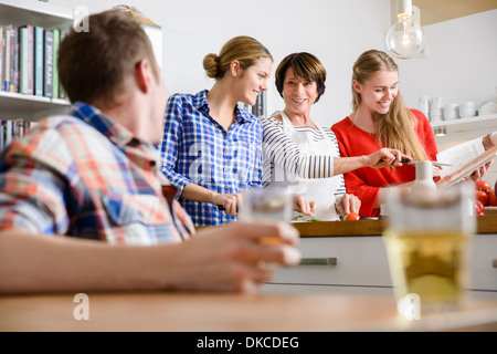 Mother, daughters and son preparing food in kitchen Stock Photo