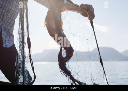 Person holding fish in net, Aure, Norway Stock Photo