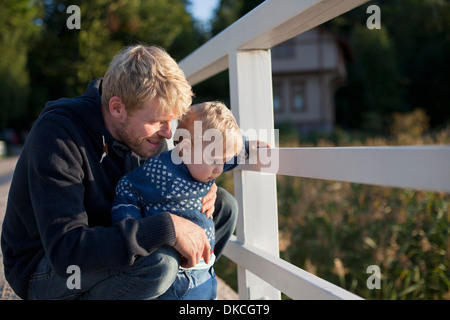 Father and toddler son looking through railing Stock Photo