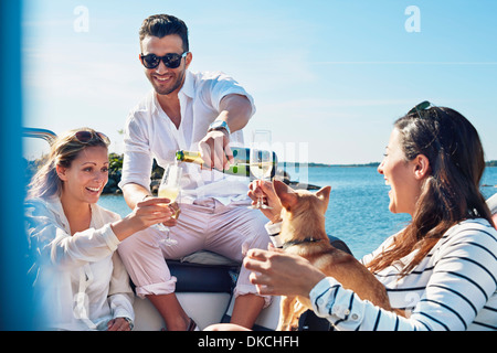 Man pouring champagne for young women on boat, Gavle, Sweden Stock Photo