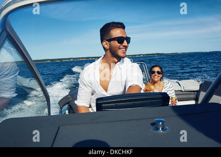 Young man steering boat with woman in background, Gavle, Sweden