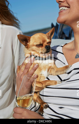 Young woman holding dog and glass of wine Stock Photo