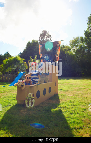 Two brothers and sister playing in garden with homemade pirate ship Stock Photo