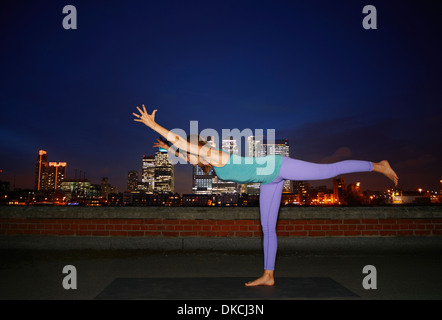 Mid adult woman practicing yoga on city rooftop Stock Photo