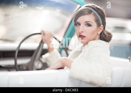 Woman at wheels of vintage car turning around Stock Photo