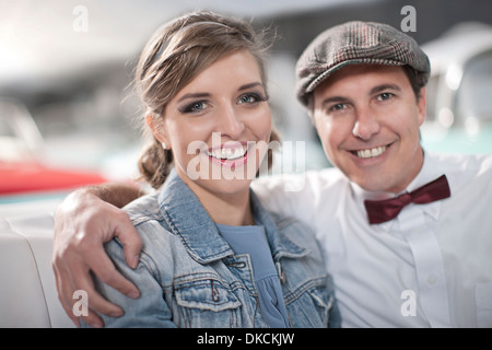 Man with arms around woman in back seat of convertible Stock Photo