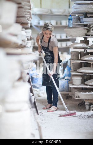 Potter sweeping floor at crockery factory Stock Photo
