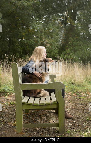 Teenage girl sitting on country bench with dog Stock Photo