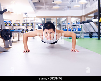 man doing push-ups on gym floor. Stock Photo