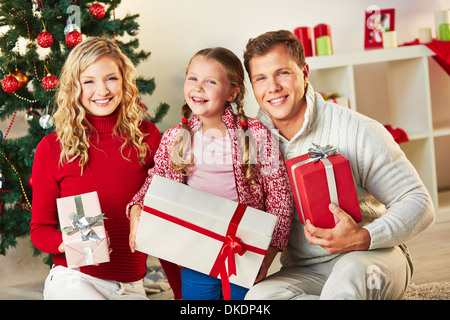 Portrait of happy family with giftboxes looking at camera on Christmas day Stock Photo