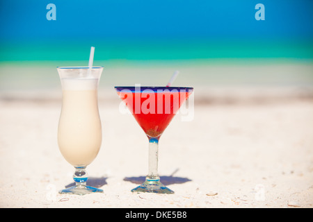 Two cocktails: pina colada and strawberry margarita on white sand beach Stock Photo