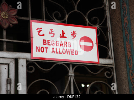 It's a photo of street board sign with the mention 'Beggars Not Allowed' in English and Chinese language with the forbidden logo Stock Photo