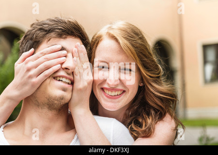 Young woman covering boyfriend's eyes Stock Photo