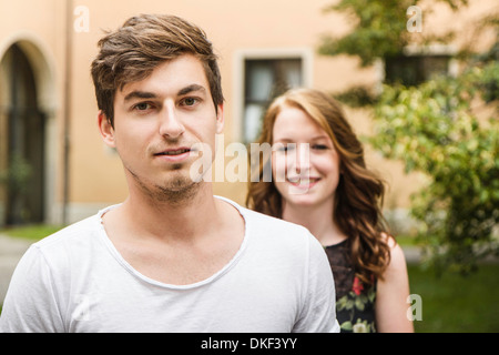 Portrait of young man with girlfriend standing in background Stock Photo