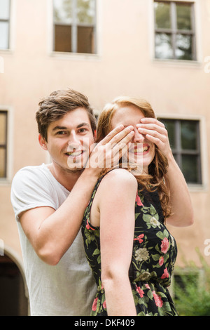 Young man covering girlfriend's eyes Stock Photo