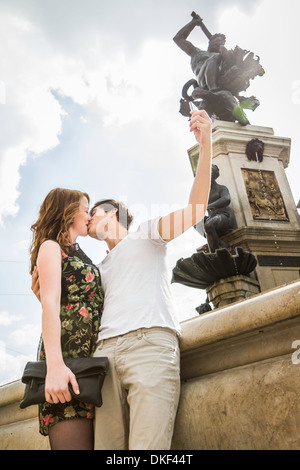 Young couple beside statue, kissing and taking self portrait photograph