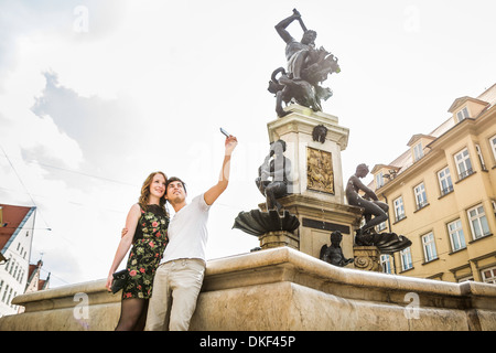 Young couple taking self portrait photograph beside statue in Augsburg, Bavaria, Germany Young couple taking self portrait photograph beside statue in Augsburg, Bavaria, Germany