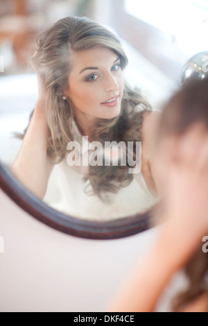 Young woman checking herself in wall mirror Stock Photo