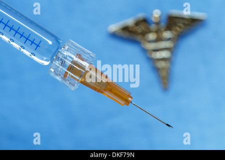 Close up of syringe with an out-of-focus caduceus in the background Stock Photo